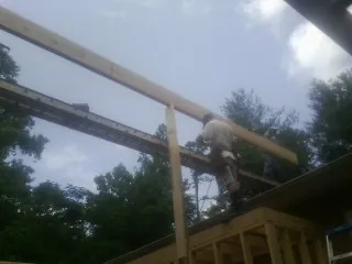 Carpenter setting a ridge beam over a new addition frame — Ice Dam Removal by Roofing Brothers in Bellmore