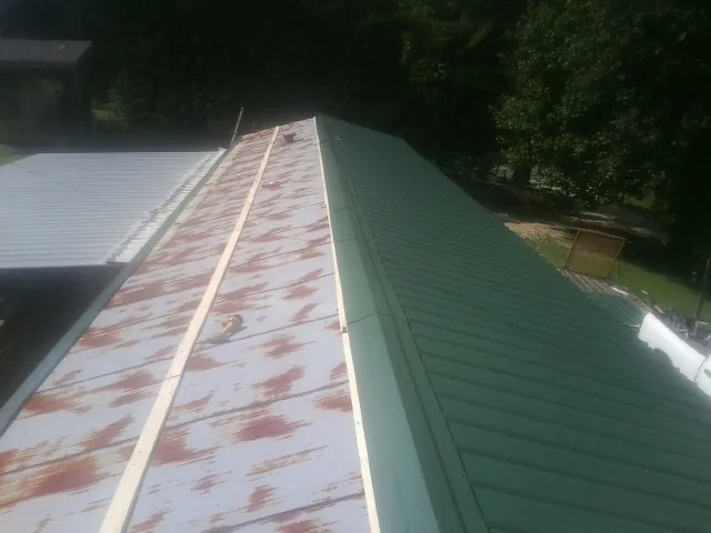 Old rusted panels beside newly installed green metal roofing — Wind Damage Roof Repair by Roofing Brothers in Bellmore
