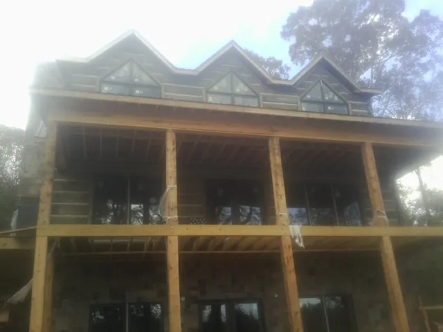 Dormers and porch framing on a large log home under construction — Roof Coating work by our crew in Bellmore