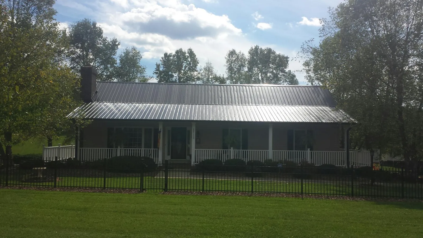 Gray metal roof on a brick ranch with a full width front porch — Gutter Guard Installation work by our crew in Bellmore