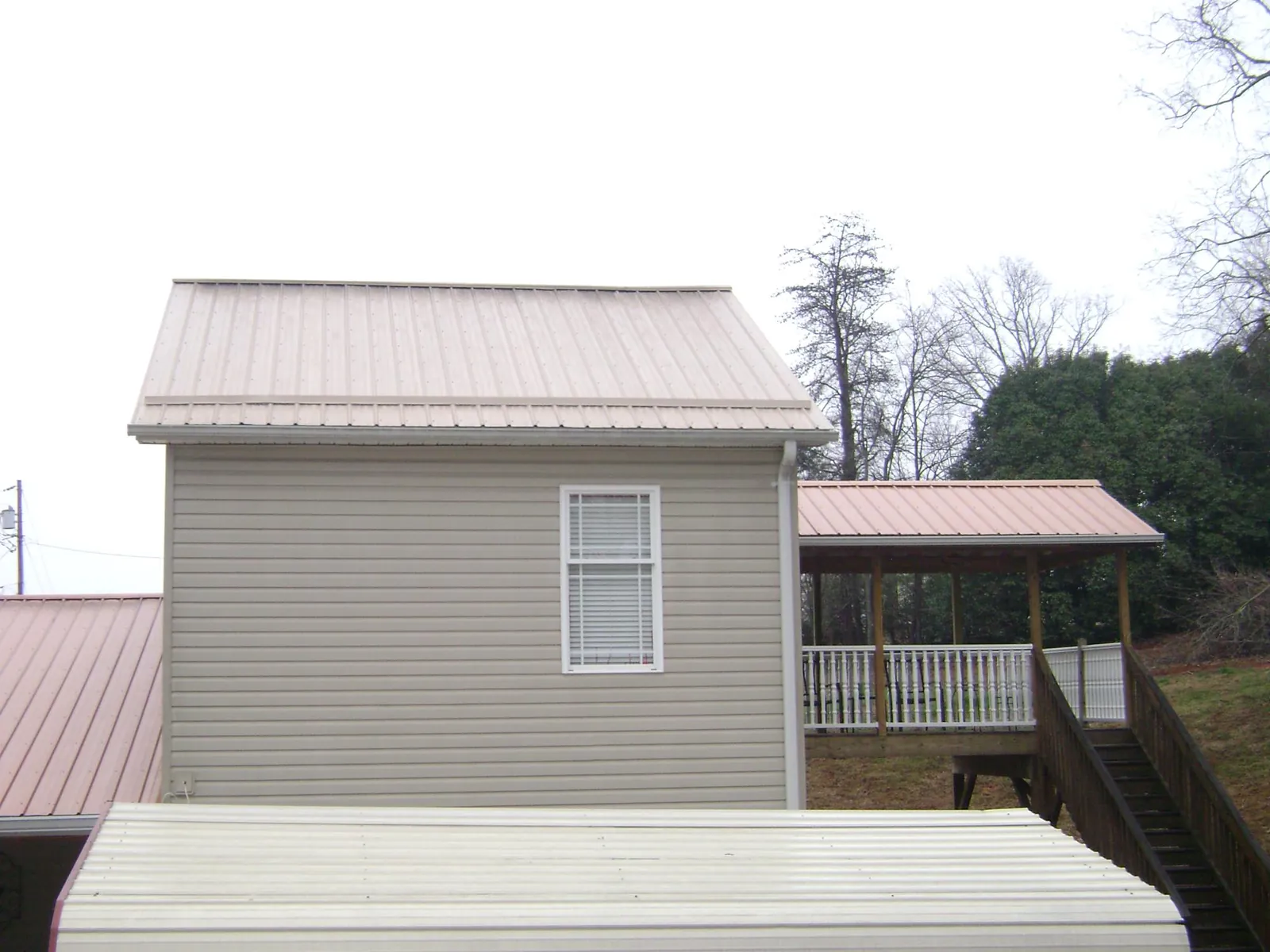 Tan metal roofs on a two story addition and attached porch, from a Roof Replacement job in Bellmore
